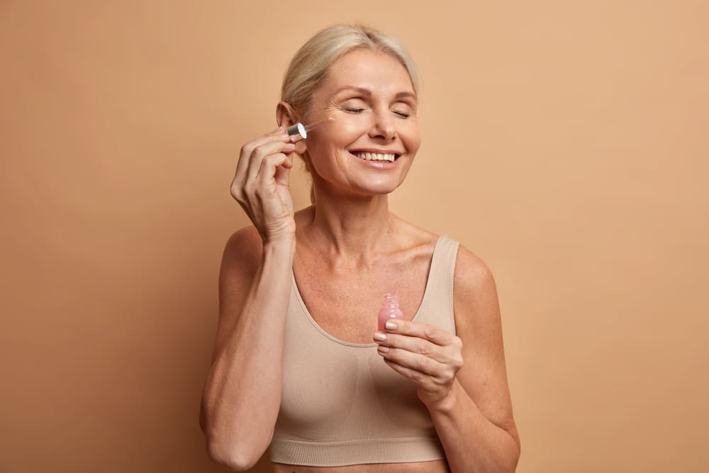 Frau mit Retinol-Serum beim Auftragen auf ihr Gesicht für Anti-Aging-Behandlung.