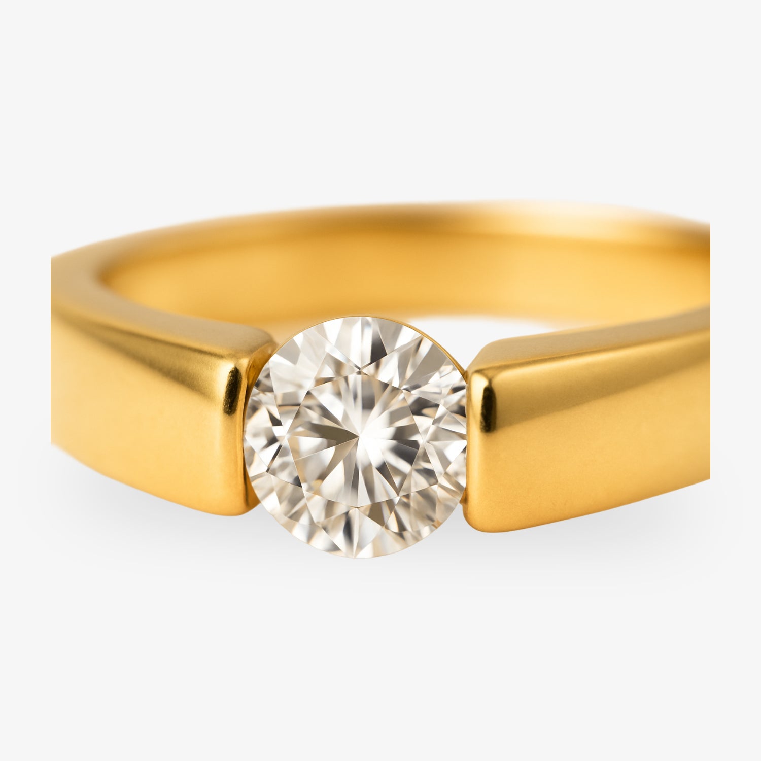 Ein goldener Ring mit einem großen, runden Diamanten in einer modernen Fassung.