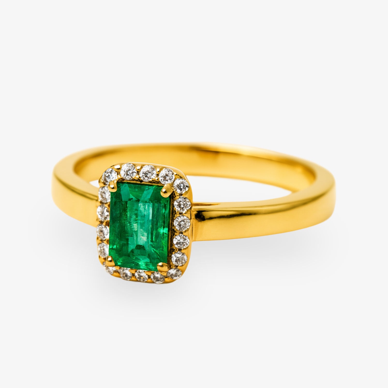 Goldener Ring mit rechteckigem Smaragd und umgebenden Diamanten auf hellem Hintergrund.