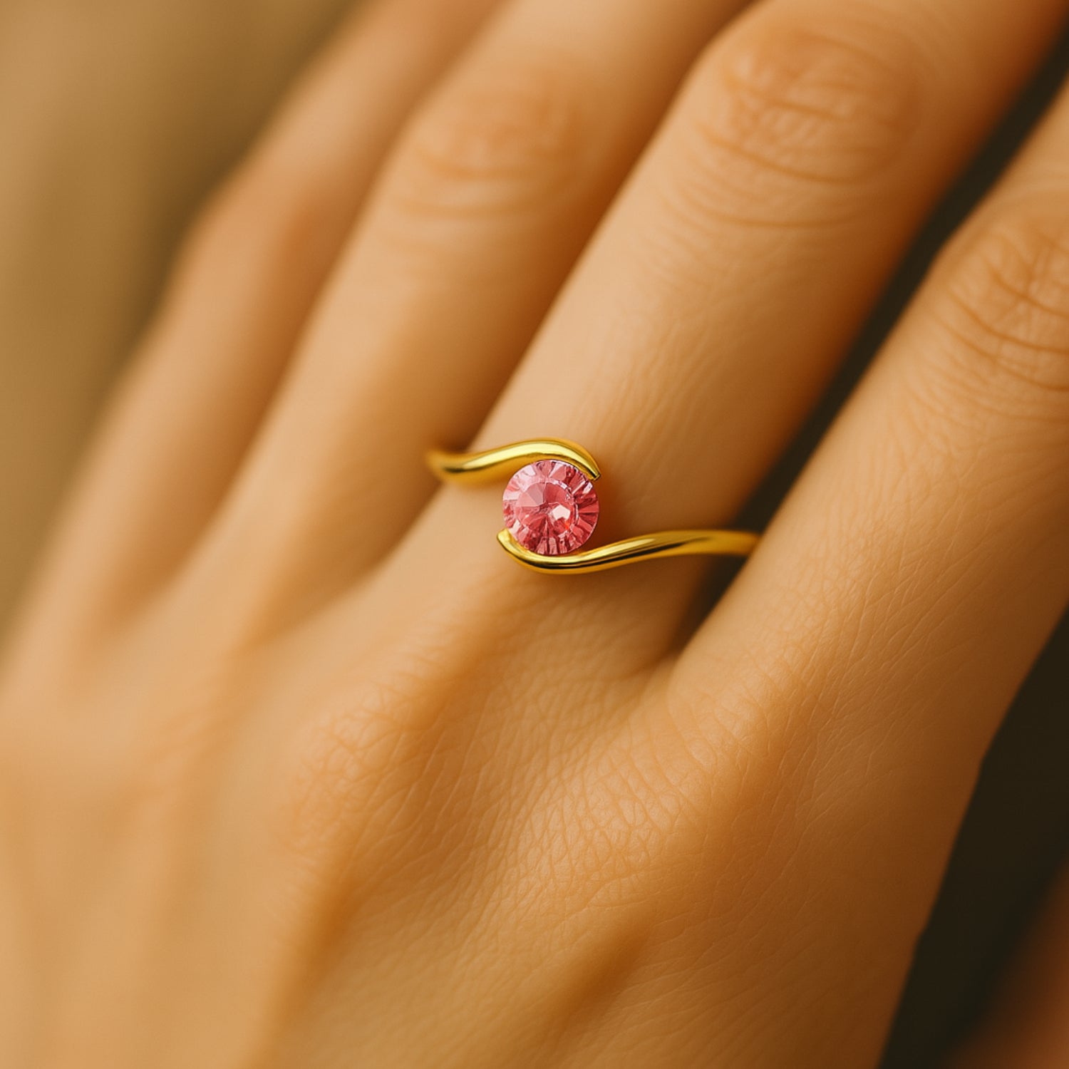 Goldener Ring mit rosafarbenem Stein auf einem Finger getragen.