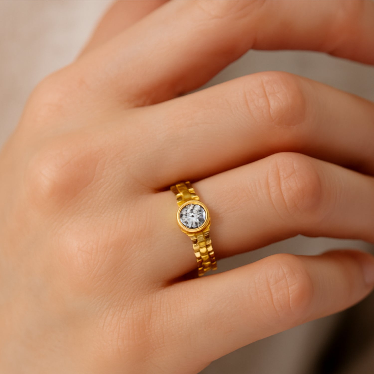Hand mit goldenem Ring und zentralem Diamanten auf einem Finger.