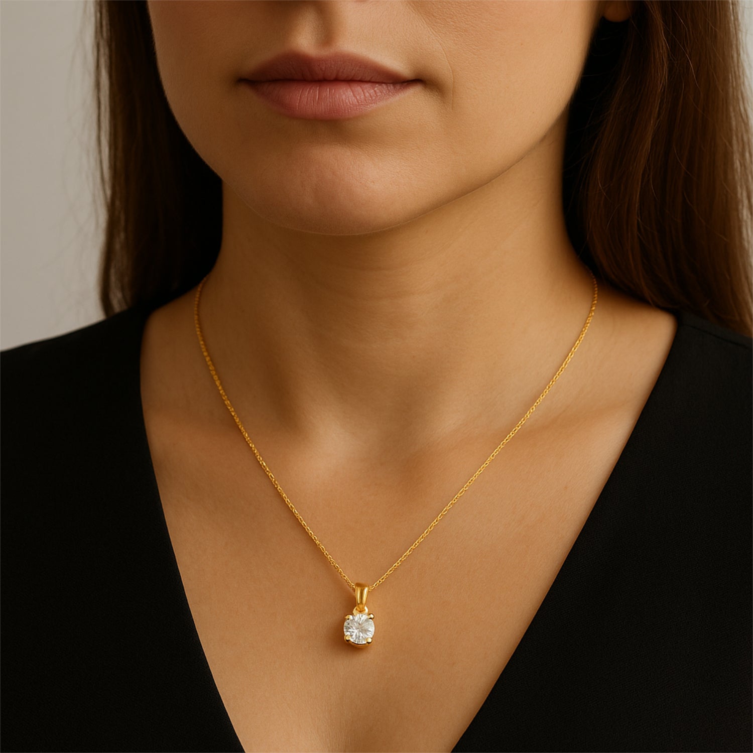 Frau trägt eine goldene Halskette mit einem glänzenden Anhänger.