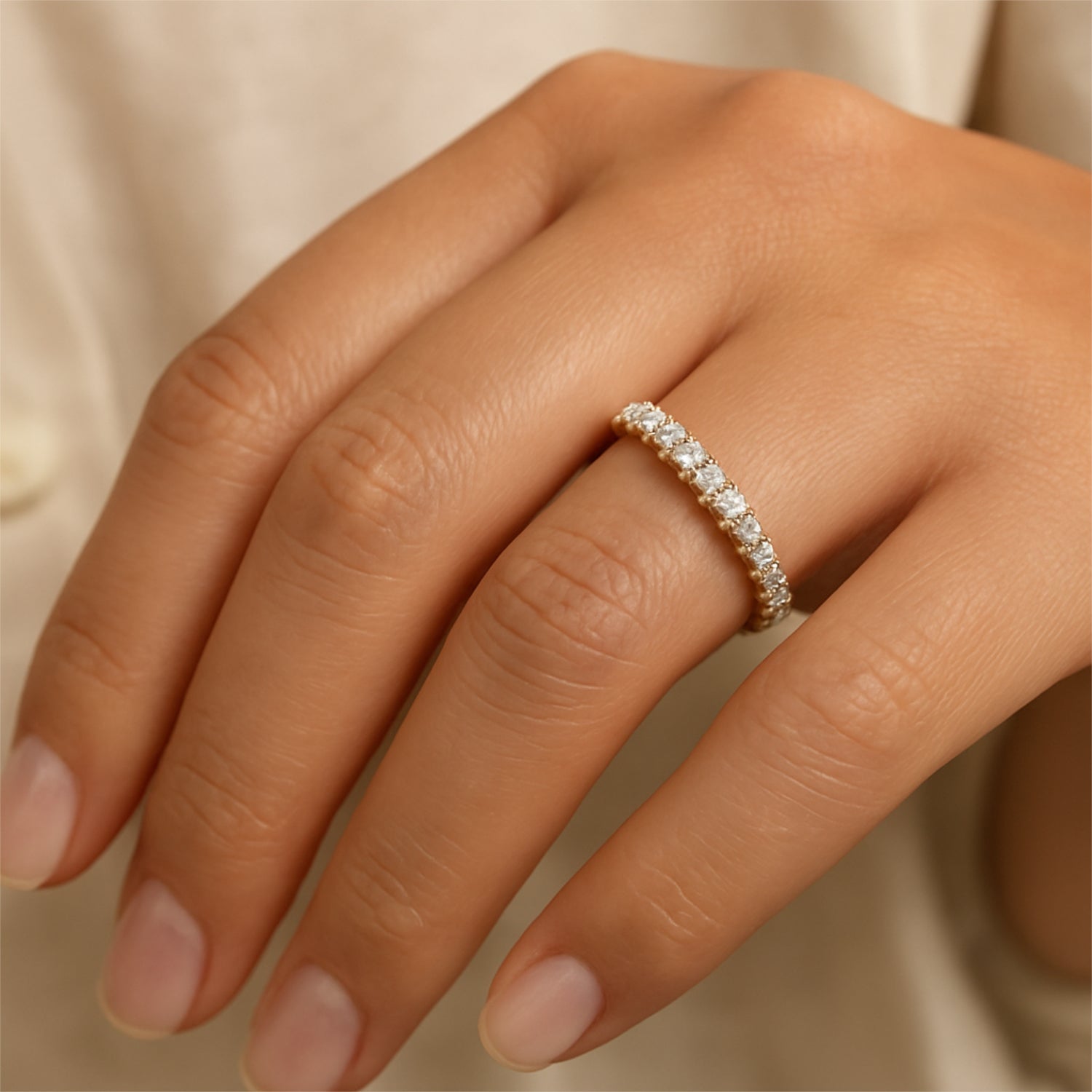 Hand mit einem goldenen Ring mit vielen kleinen Diamanten auf dem Ringfinger.