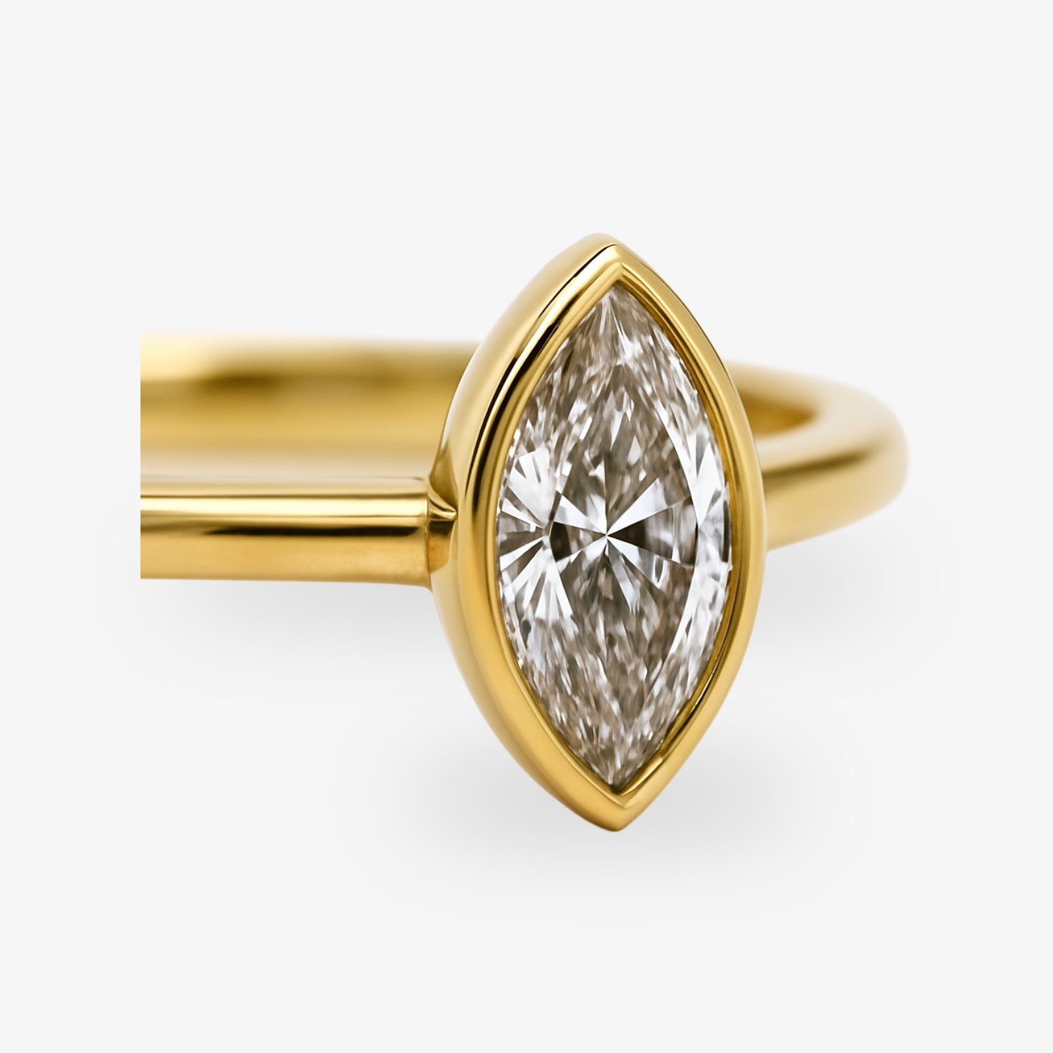 Goldener Ring mit marquiseförmigem Diamanten in der Fassung auf weißem Hintergrund.