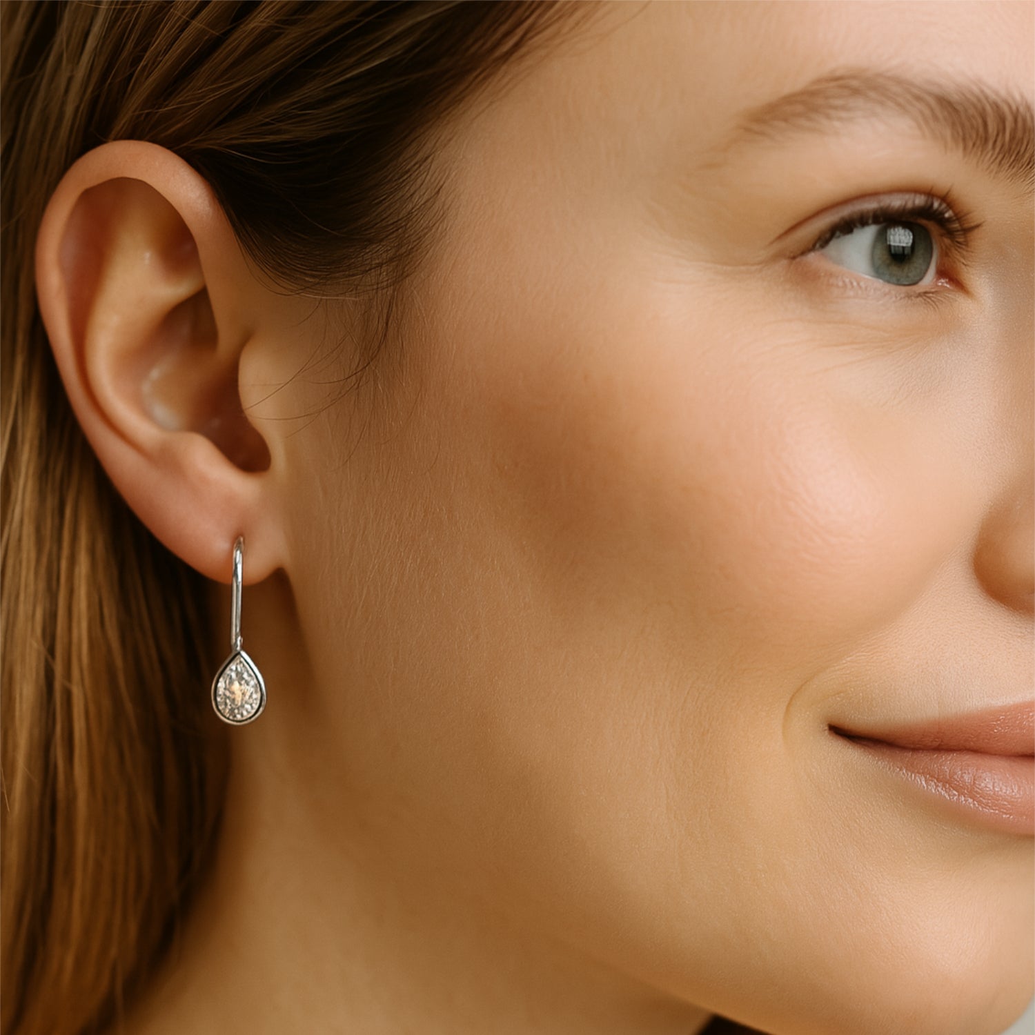 Nahaufnahme von einer lächelnden Frau mit einem Tropfen-Ohrring am linken Ohr.