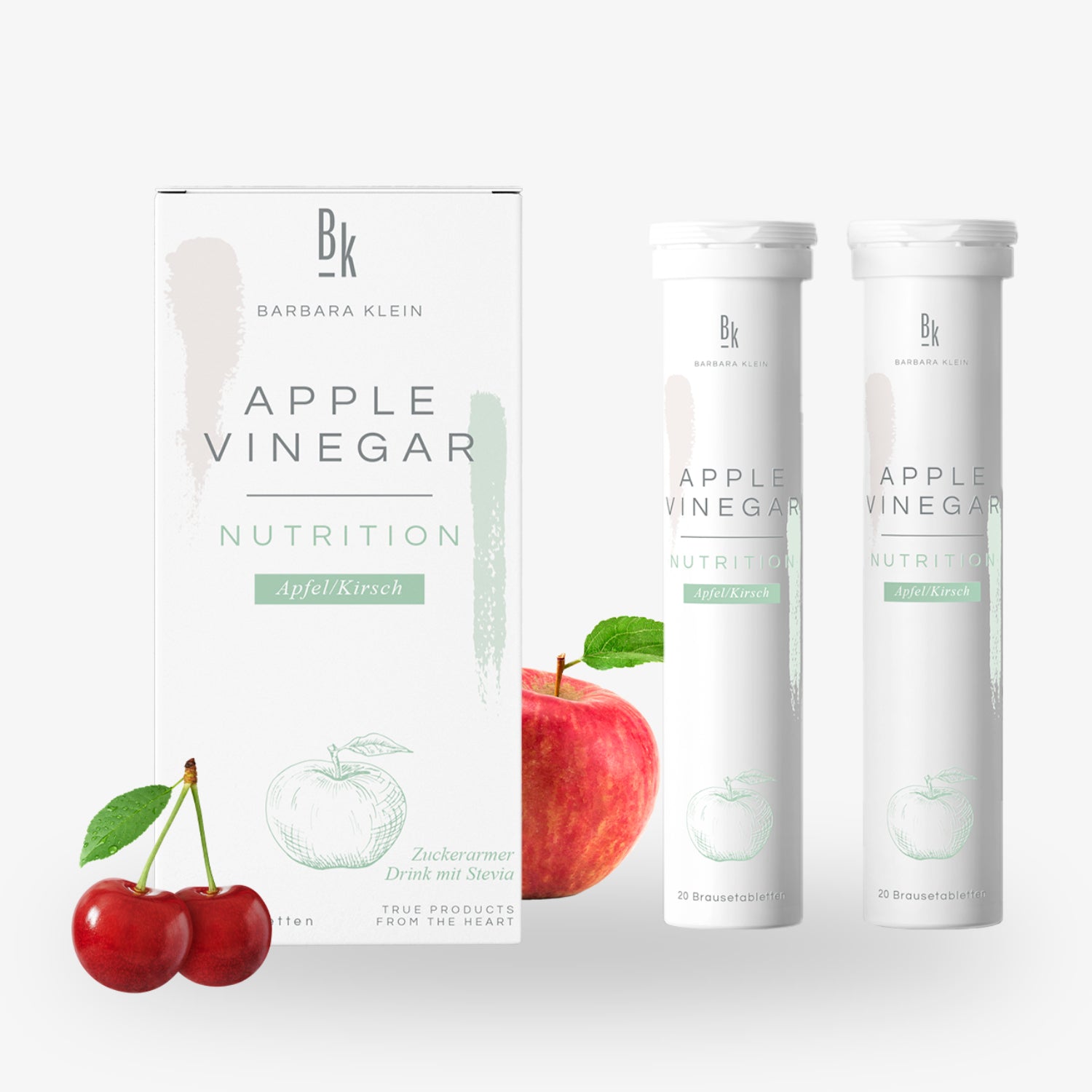 Verpackung von Apfelessig-Tabletten mit Apfel- und Kirschelementen, Stevia-Geschmack, neben einer Kirsche und einem Apfel.