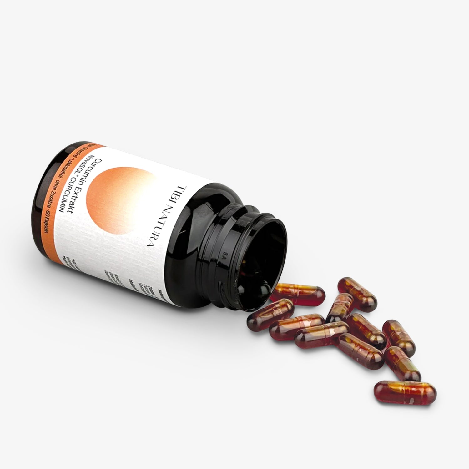 Schwarze Pillendose liegt offen auf der Seite mit Kapseln, die herausgefallen sind.