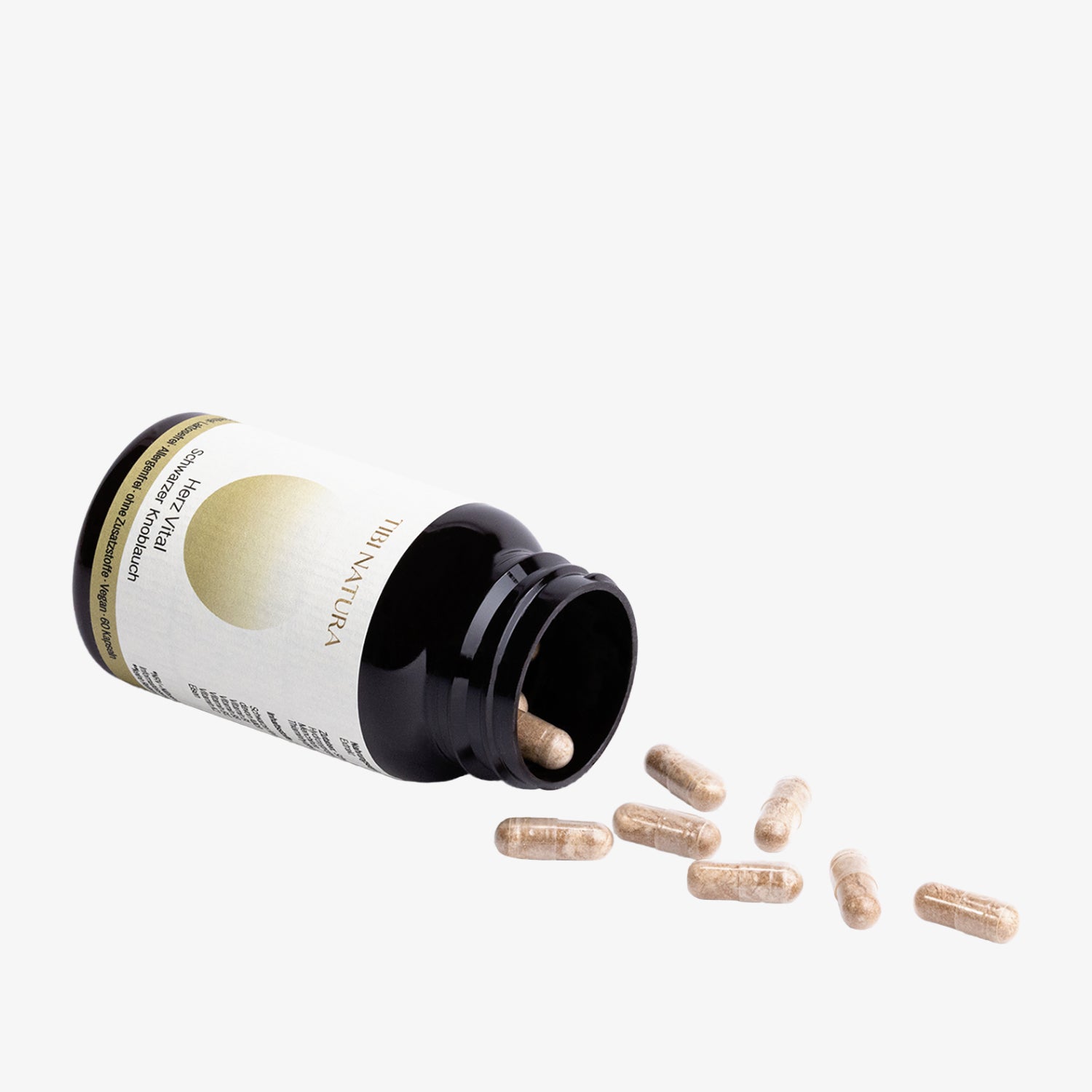 Schwarze Pillendose mit Naturprodukt-Label, geöffnet mit mehreren Kapseln, die auf einer weißen Oberfläche verstreut sind.