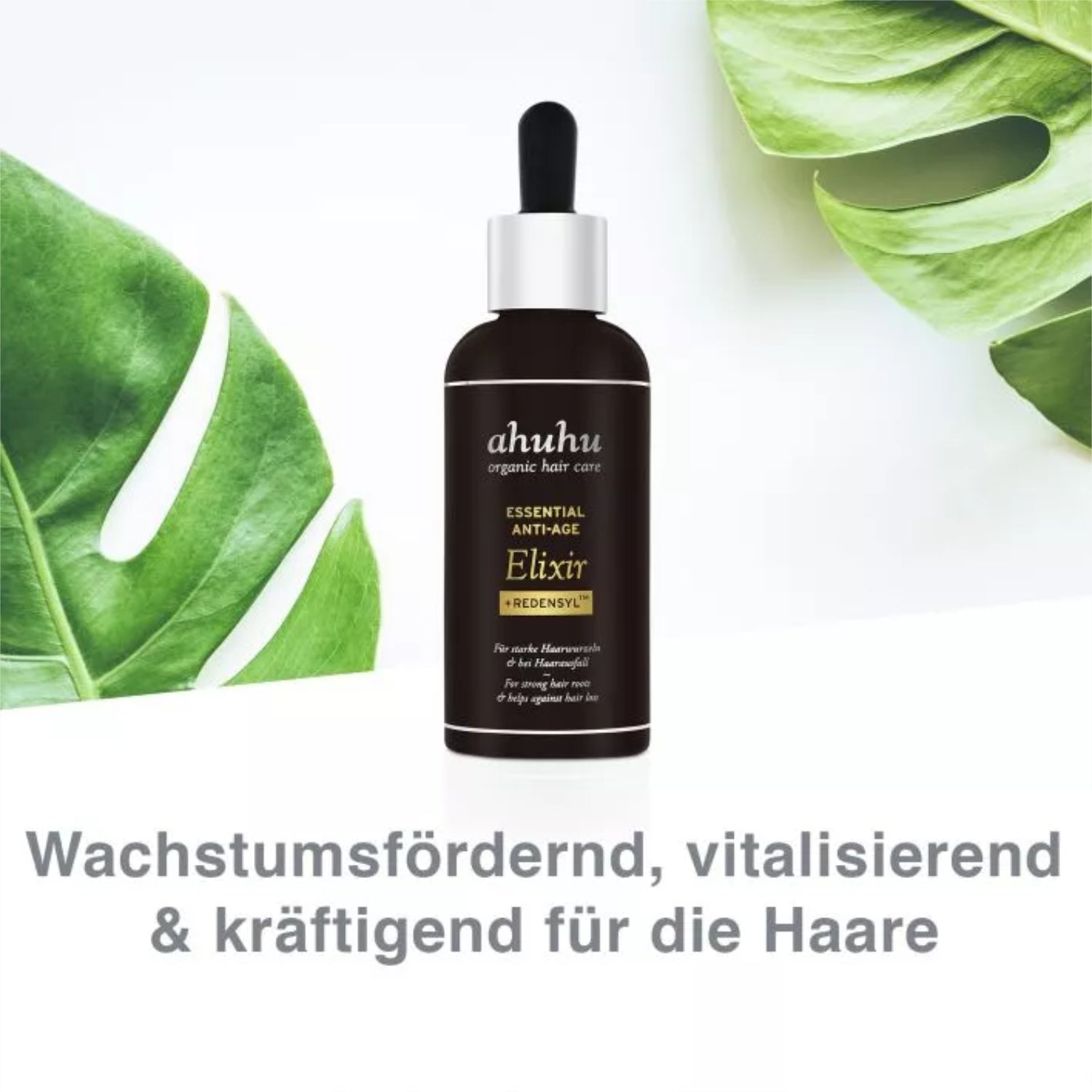 Dunkle Flasche Ahuhu Essential Anti-Age Elixir mit Pipette vor grünen Blättern und Text zur Haarpflegestärkung.