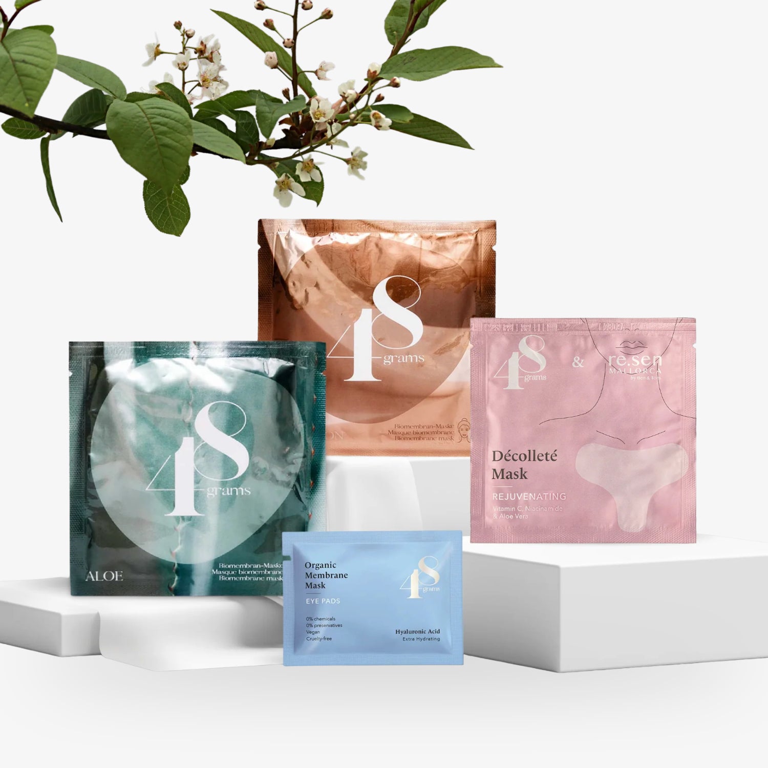 Verschiedene Beauty-Masken auf weißen Podesten, dahinter blühende Zweige.