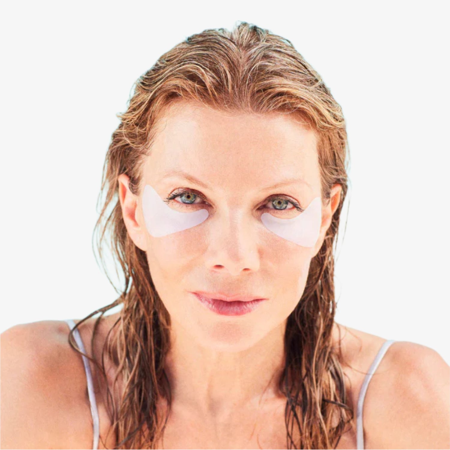 Frau mit nassen Haaren trägt weiße Augenpads unter den Augen.