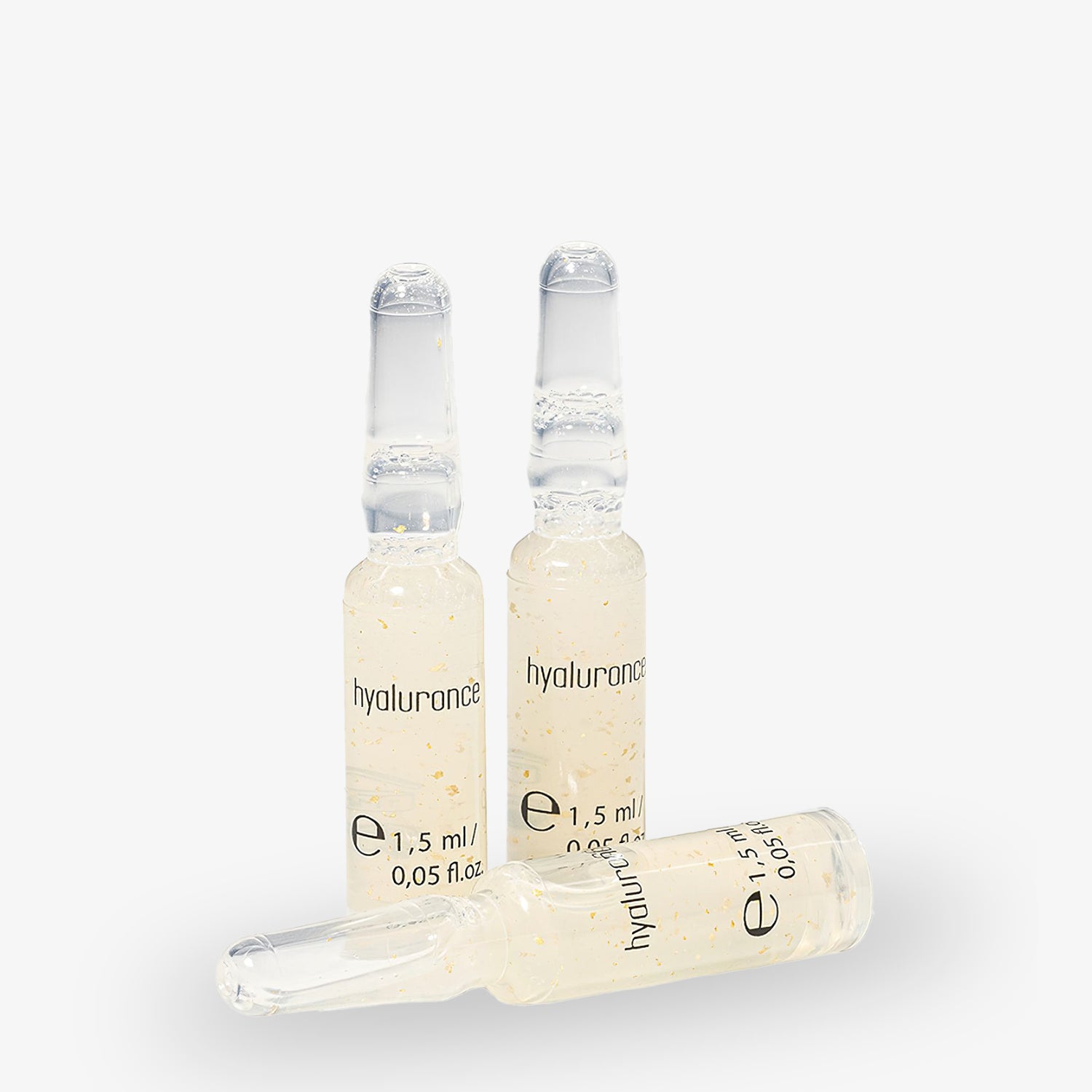 Drei Glasampullen mit Hyaluronsäure, zwei stehend und eine liegend, auf weißem Hintergrund.