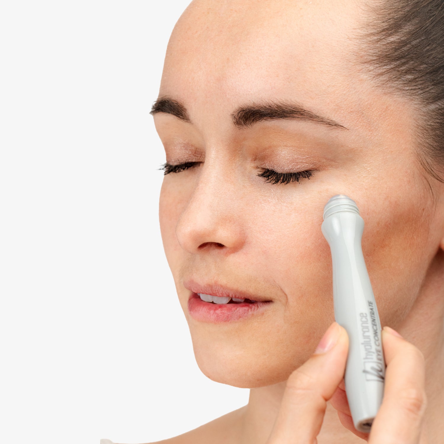 Frau trägt mit einem Roll-on-Applikator ein Pflegeprodukt auf die Haut um ihr Auge auf.