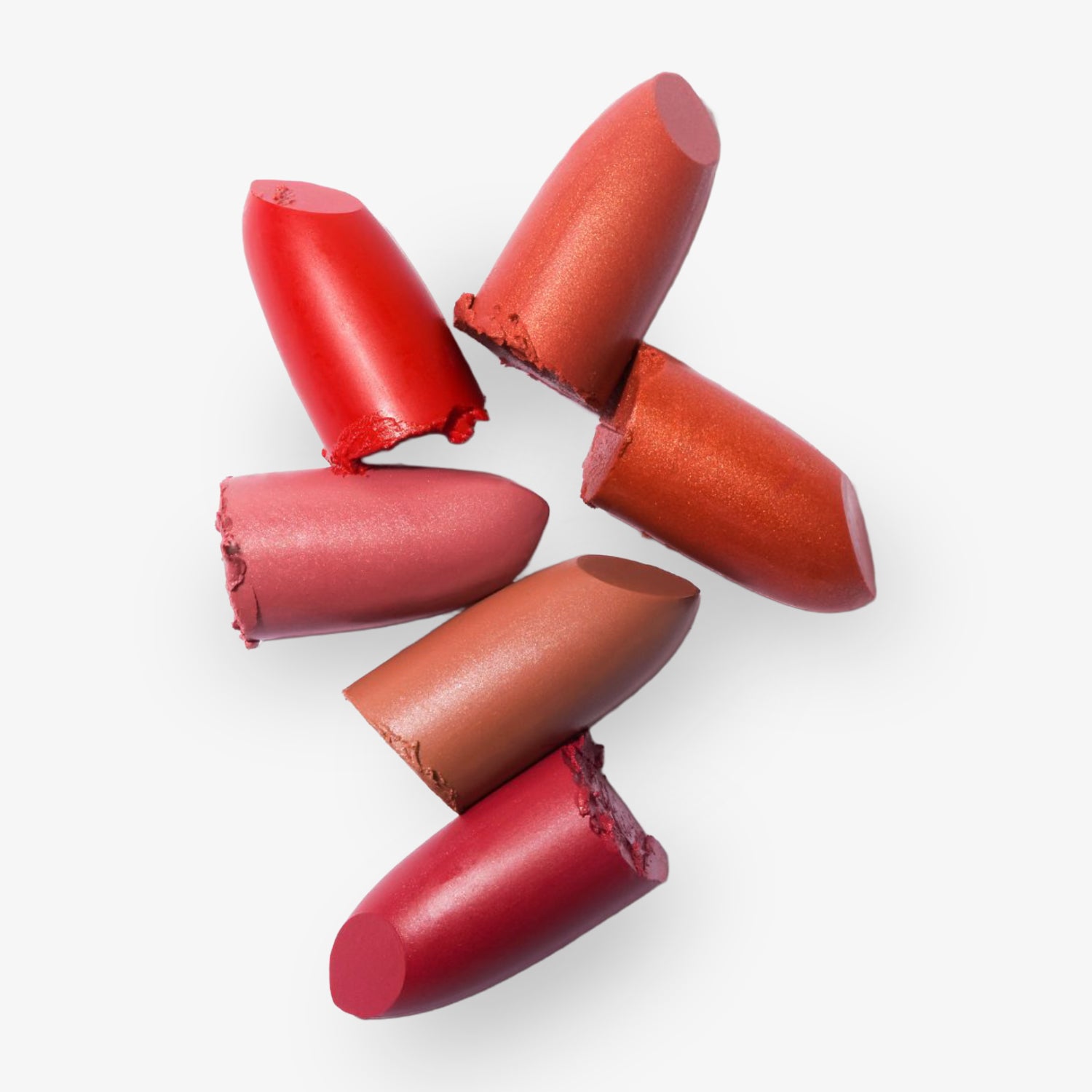 Sechs abgebrochene Lippenstiftstücke in verschiedenen Rottönen liegen auf einem weißen Hintergrund.