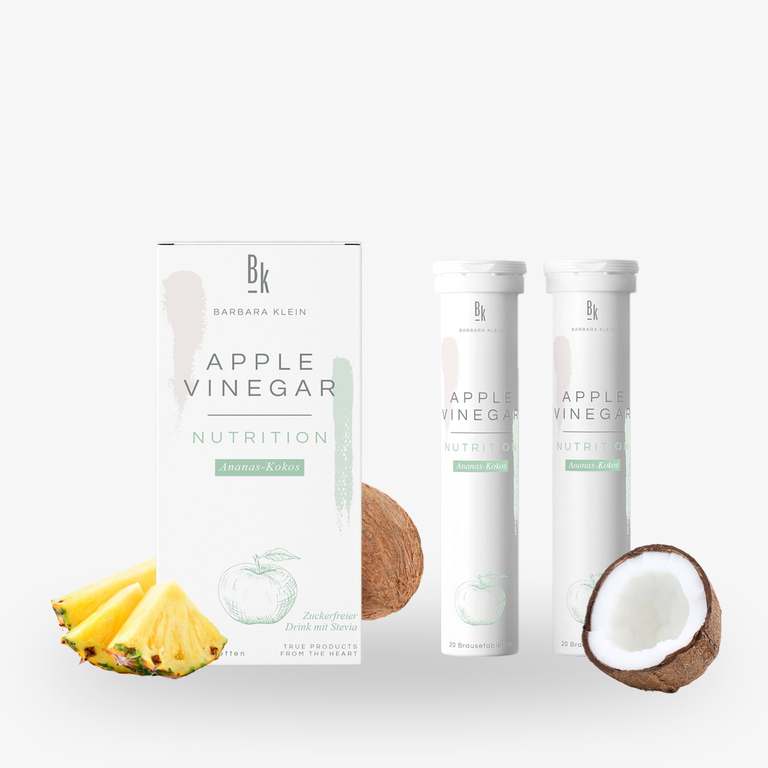 Packung und zwei Flaschen Apfelessig-Nahrung mit Ananas und Kokosnuss, daneben eine halbe Kokosnuss und Ananasstücke.