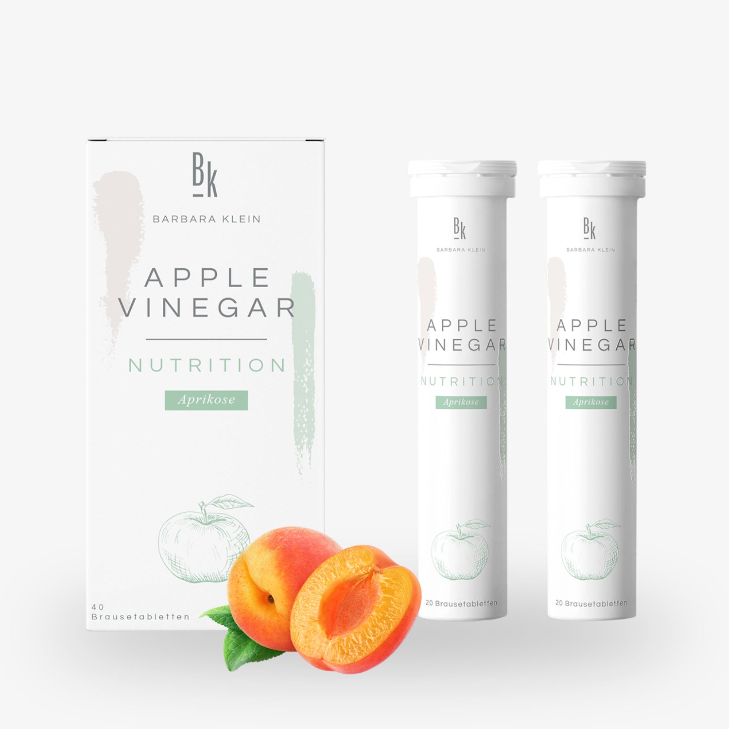 Schachtel und zwei Röhren mit Apfelessig-Nahrungsergänzung Aprikose, daneben frische Aprikosen.