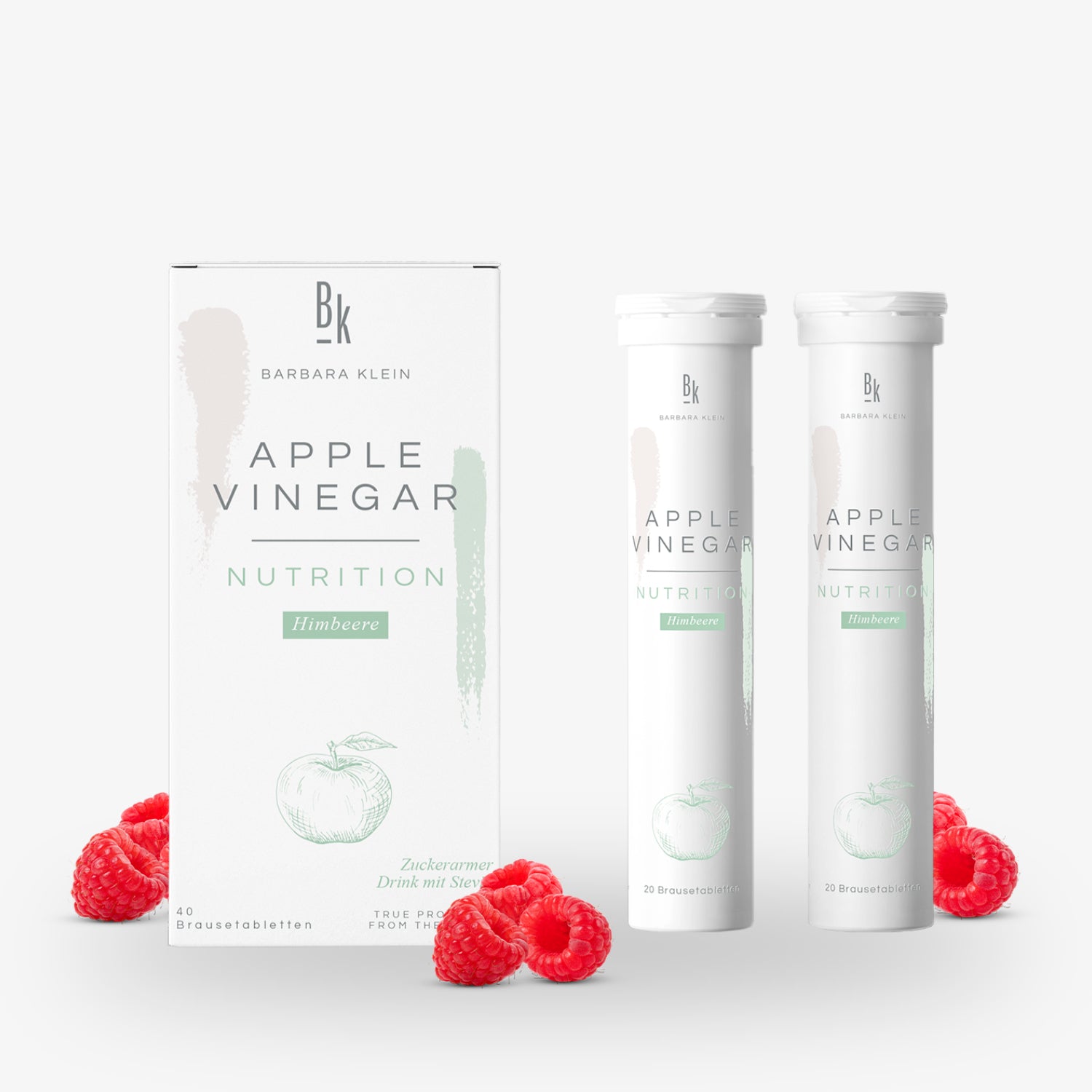 Verpackung und zwei Röhren Apfelessig-Tabletten mit Himbeergeschmack, umgeben von frischen Himbeeren.