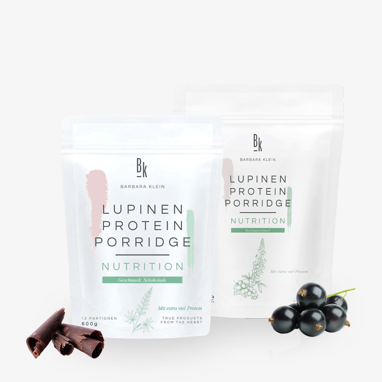 Zwei Packungen Lupinen Protein Porridge mit Schokoladenstücken und Schwarzen Johannisbeeren davor.