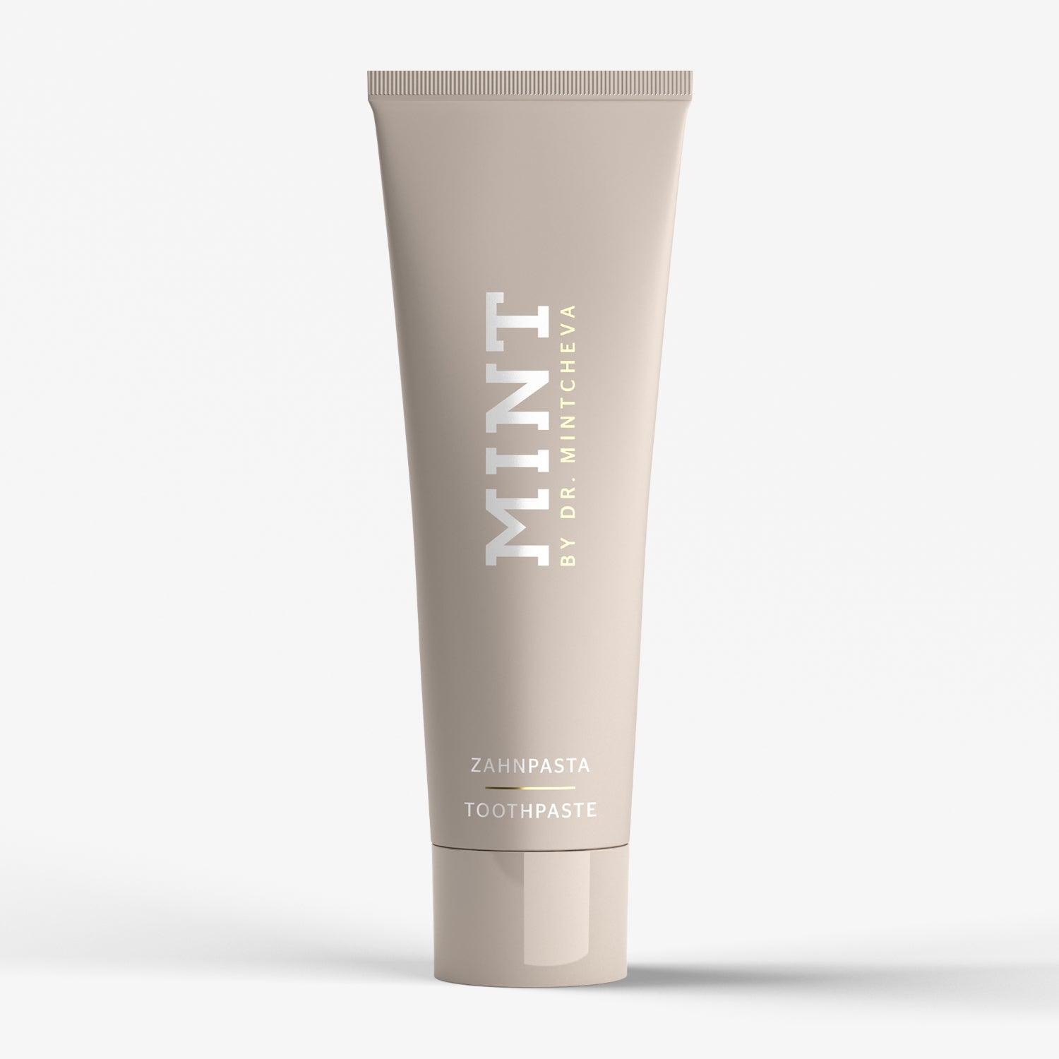 Beige Zahnpastatube mit der Aufschrift "MINT BY DR. MINTCHEVA" und "ZAHNPASTA TOOTHPASTE" auf weißem Hintergrund.