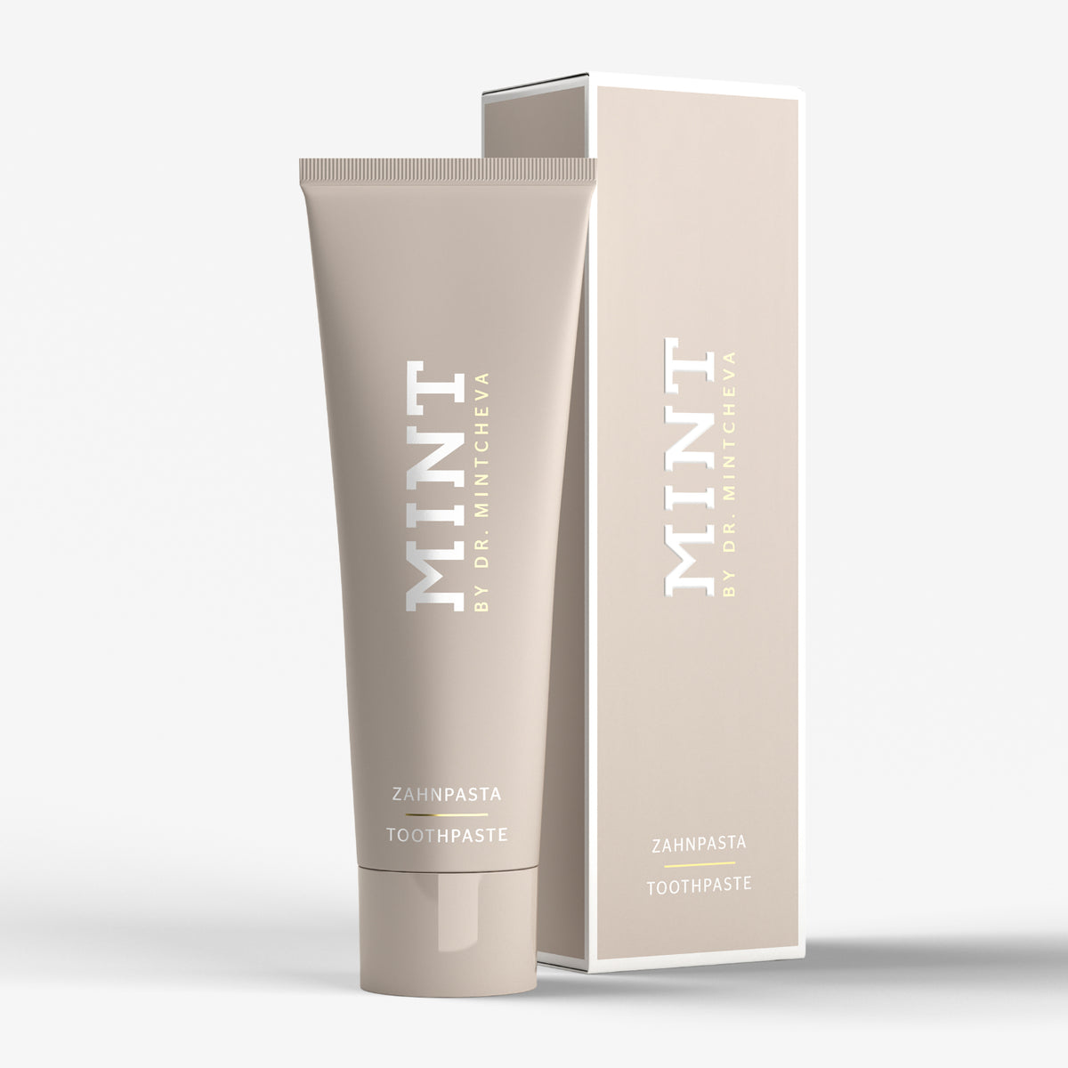 Beige Tube und Verpackung von Zahnpasta mit der Aufschrift "MINT BY DR. MINTCHEVA" auf weißem Hintergrund.