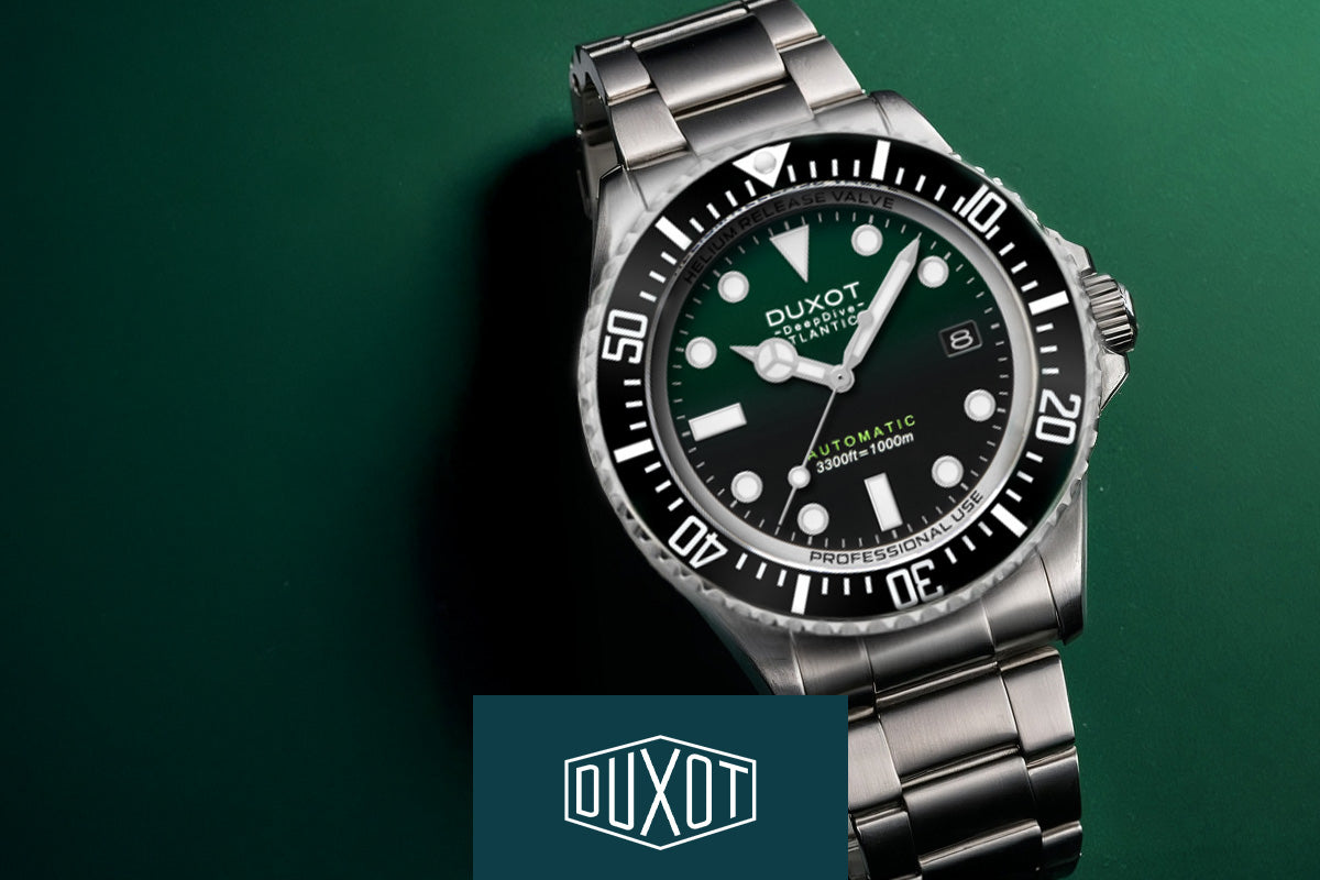 Silberne Taucheruhr mit grünem Zifferblatt auf grünem Hintergrund, darunter das Duxot-Logo.
