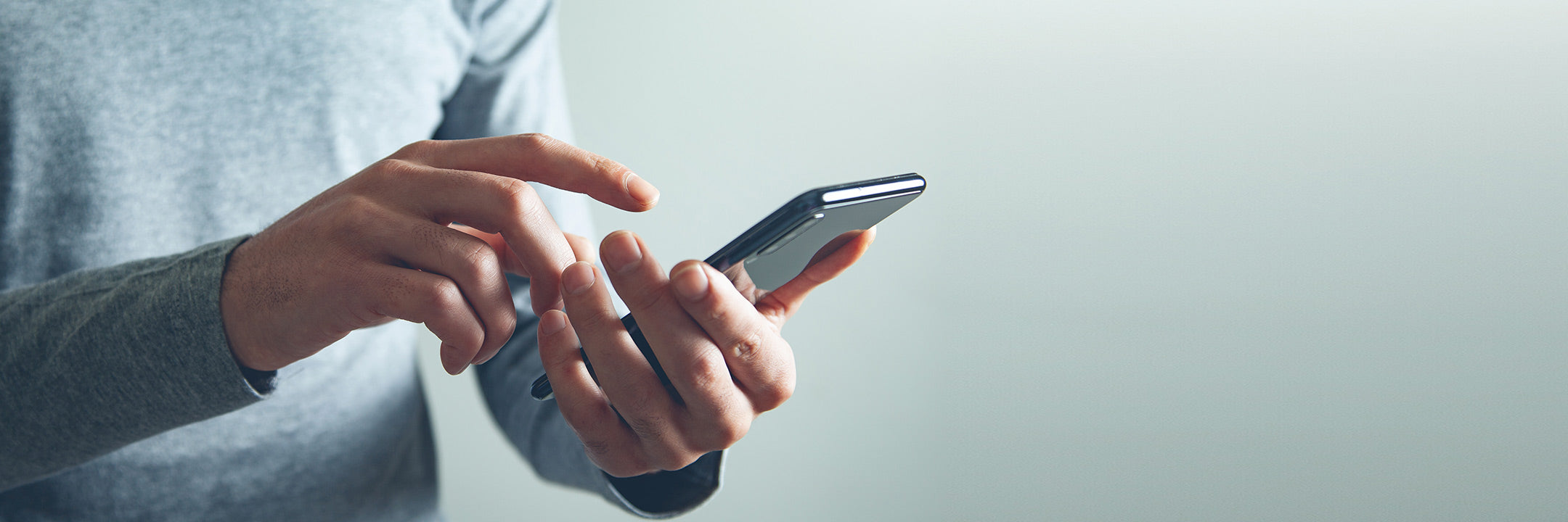 Person hält ein Smartphone in der Hand und tippt darauf.