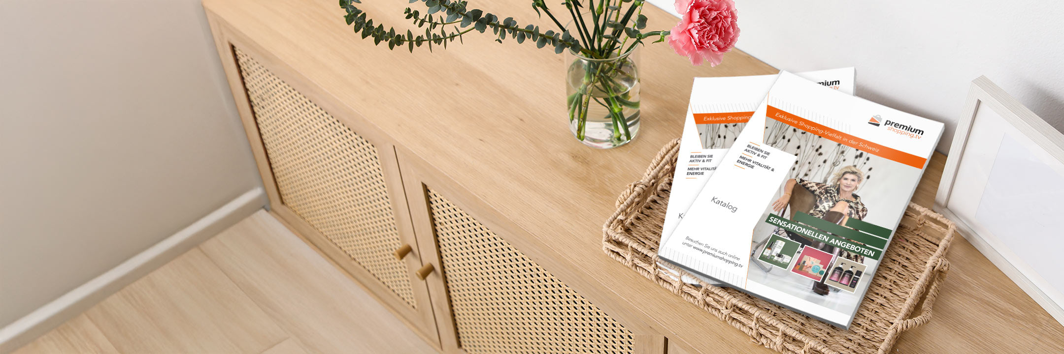 Ein Holzmöbelstück mit zwei Zeitschriften, einer Vase mit rosa Blume und einem leeren Bilderrahmen darauf.