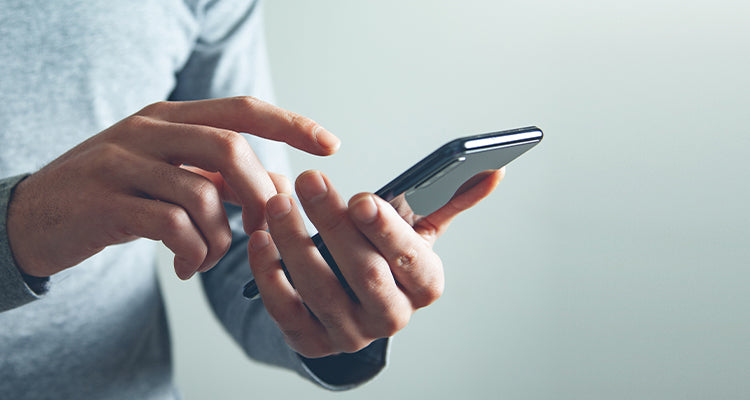 Person tippt auf Smartphone in der Hand.