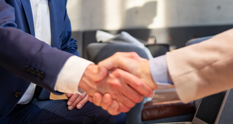 Zwei Personen schütteln sich die Hand in einem geschäftlichen Umfeld.