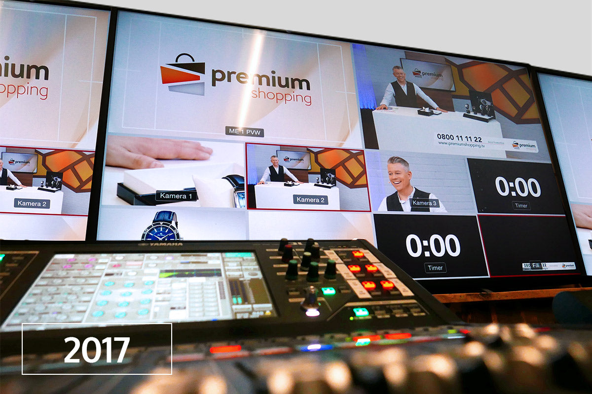 Regiepult mit Bildschirmen, die eine Verkaufssendung namens "premium shopping" zeigen; im Vordergrund ist 2017 zu sehen.