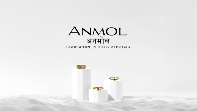 Drei goldene Ringe auf weißen Sockeln vor einem weißen Hintergrund, darüber der Text "ANMOL" und "UNBESCHREIBLICH & KOSTBAR".