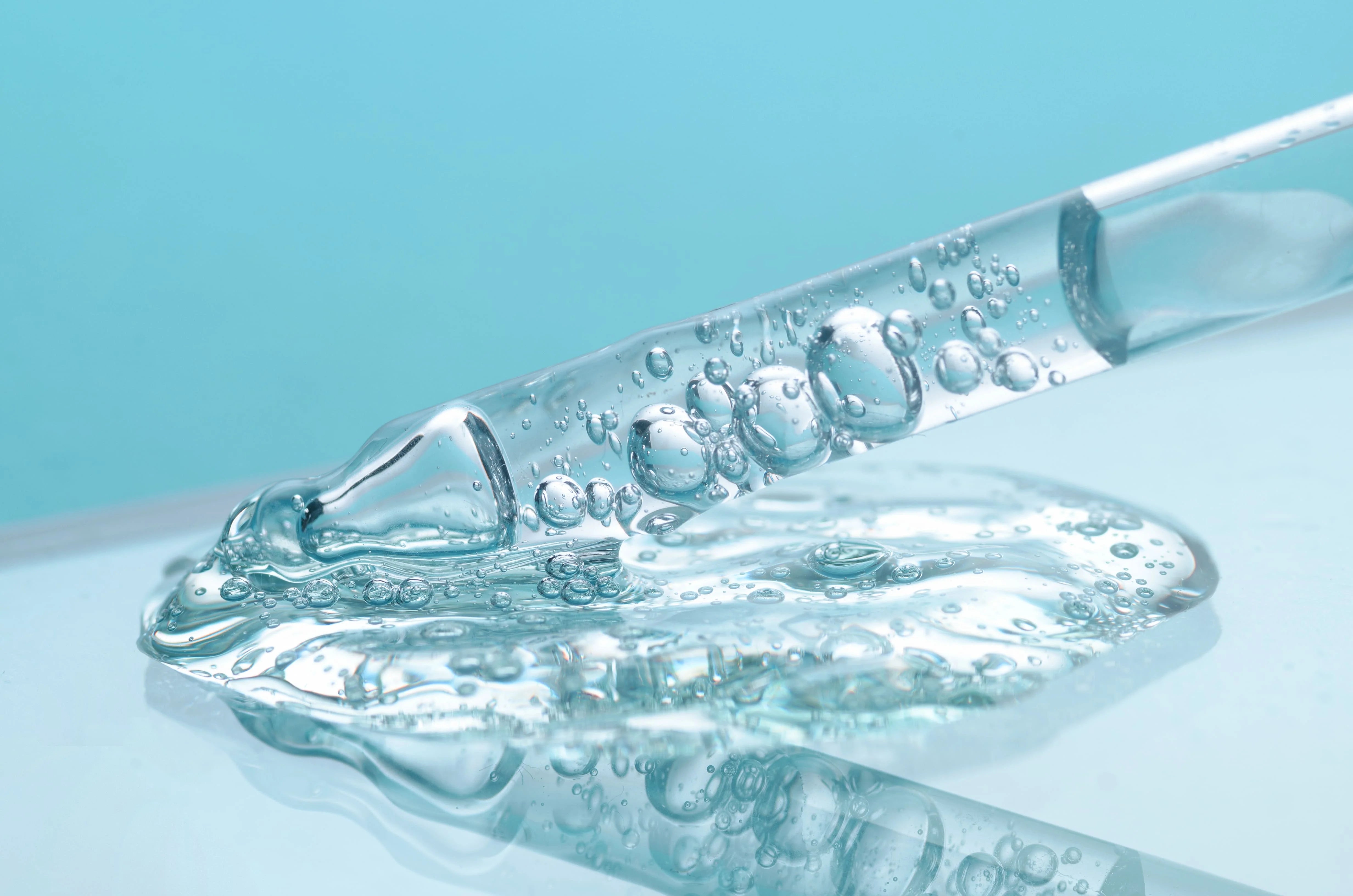 Hyaluronsäure erklärt: Warum jede Haut diesen Wirkstoff braucht, mit Tröpfchen in einer Pipette auf Wasseroberfläche.