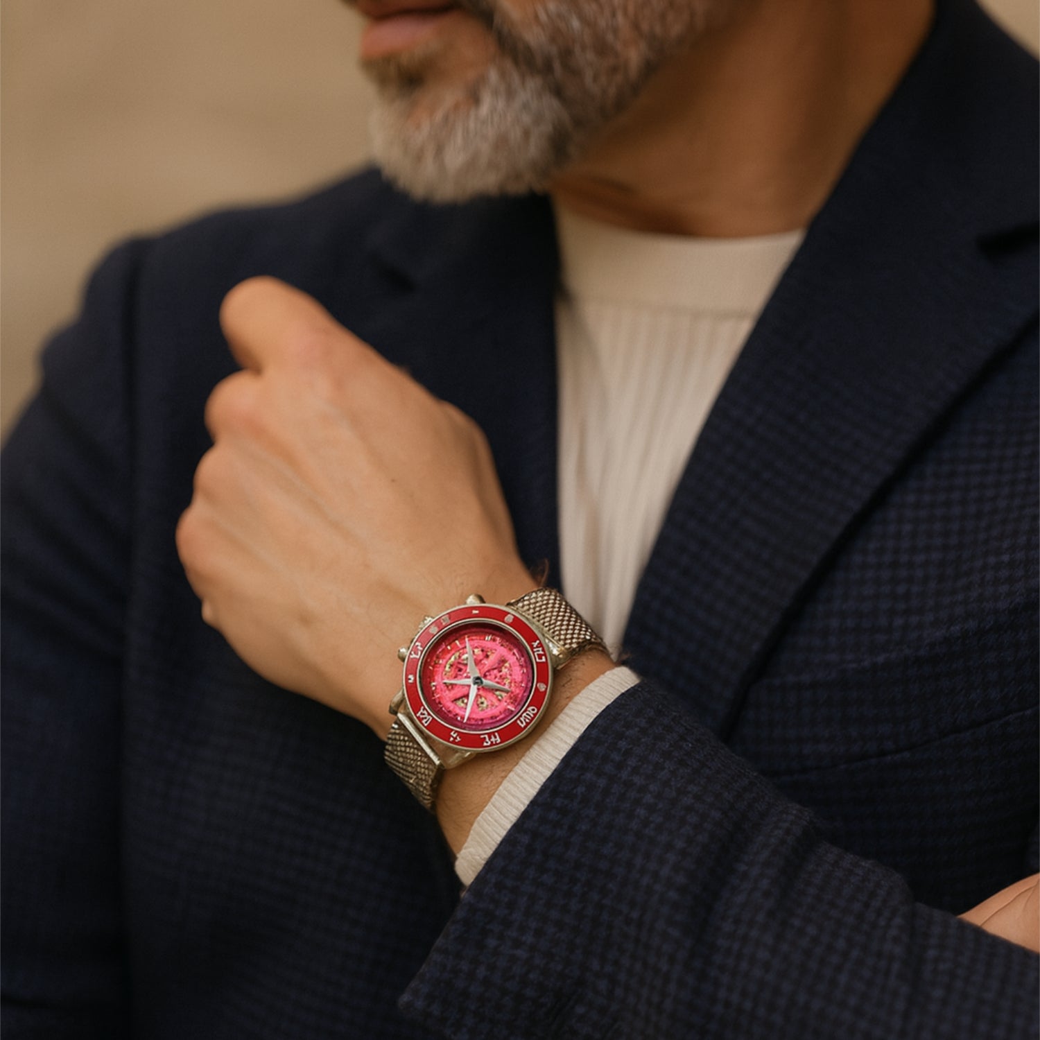Mann in blauem Anzug trägt eine Uhr mit rotem Zifferblatt und Mesh-Armband.