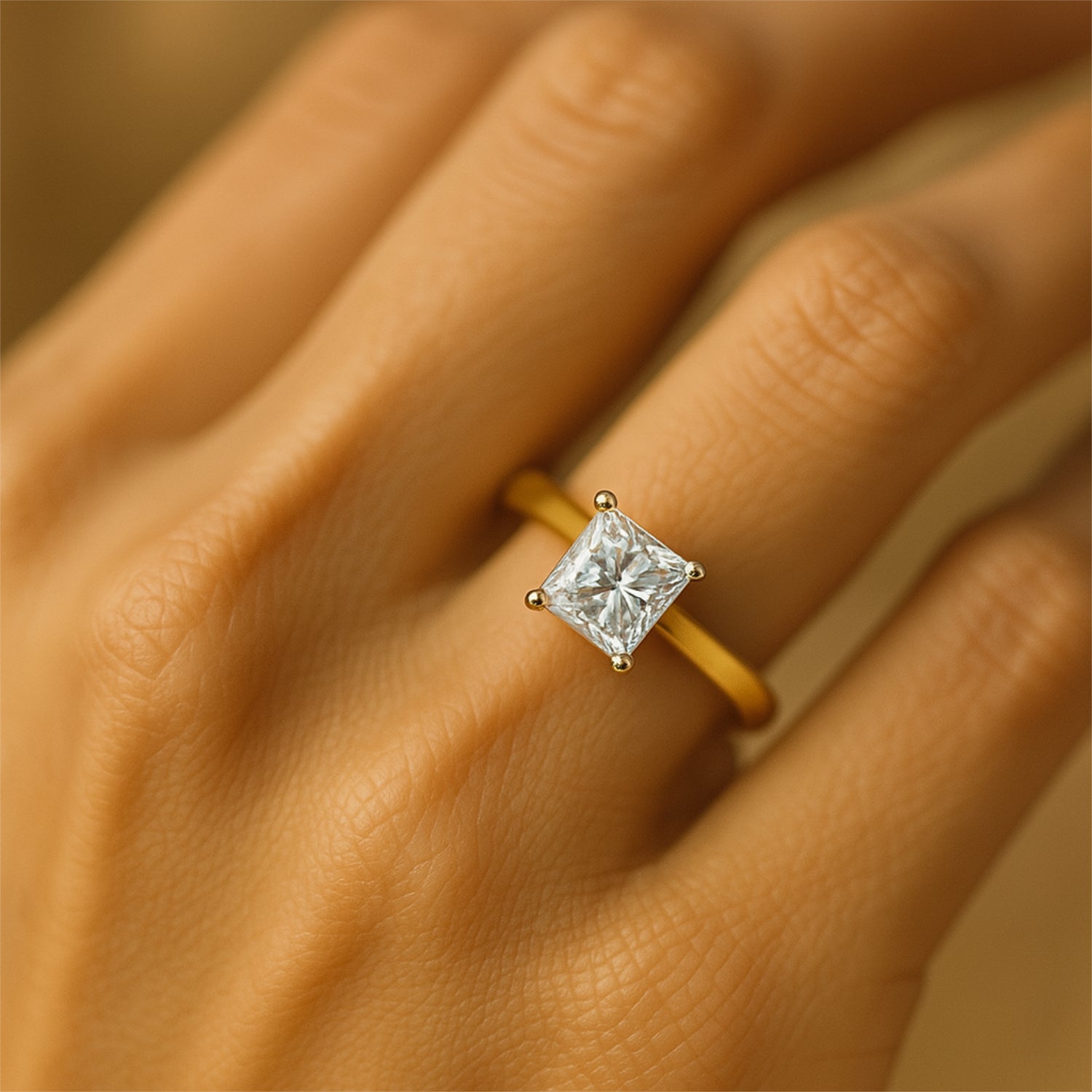 Nahaufnahme einer Hand mit einem goldenen Ring, der einen quadratischen Diamanten trägt.