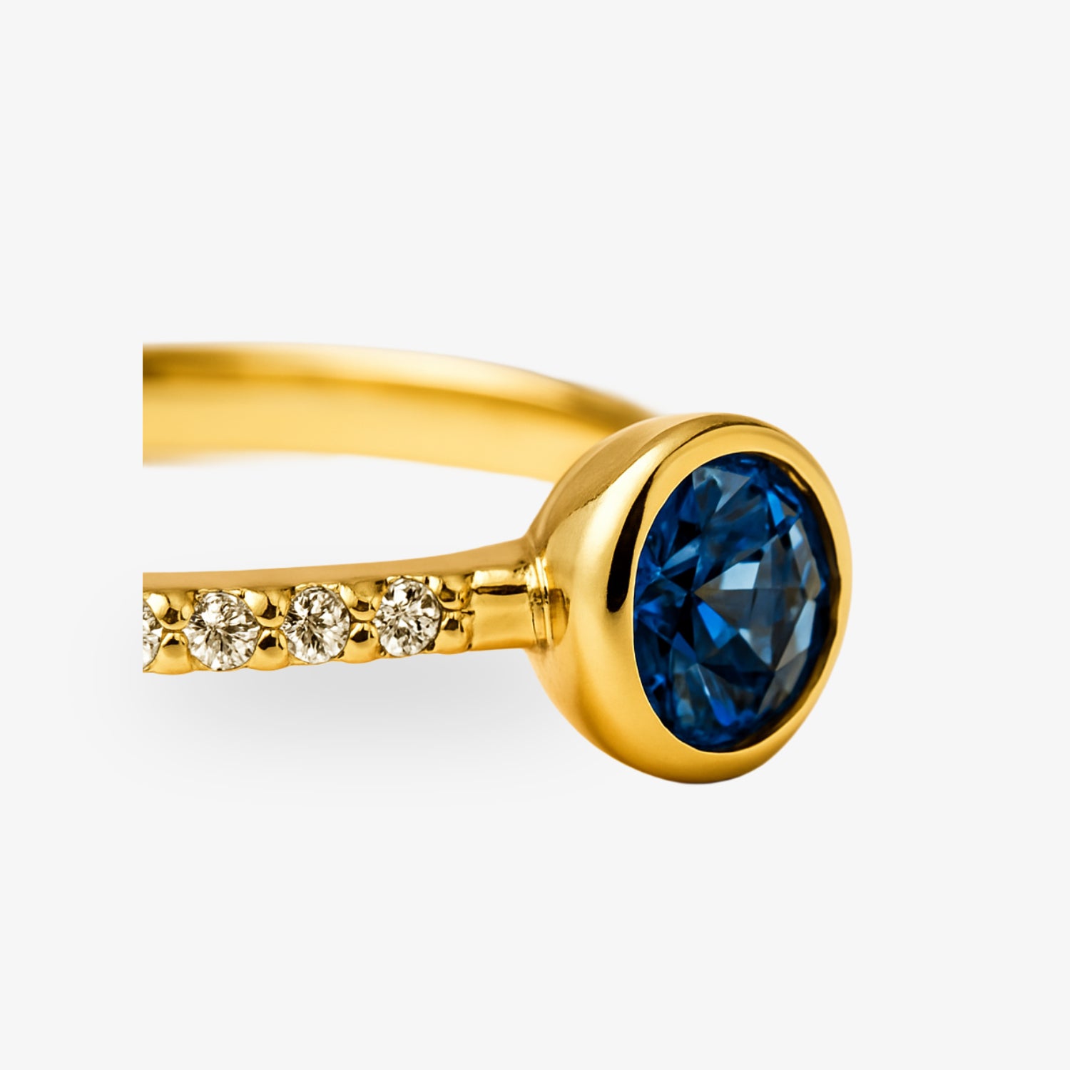 Goldener Ring mit einem blauen Edelstein und kleinen Diamanten am Ringband.