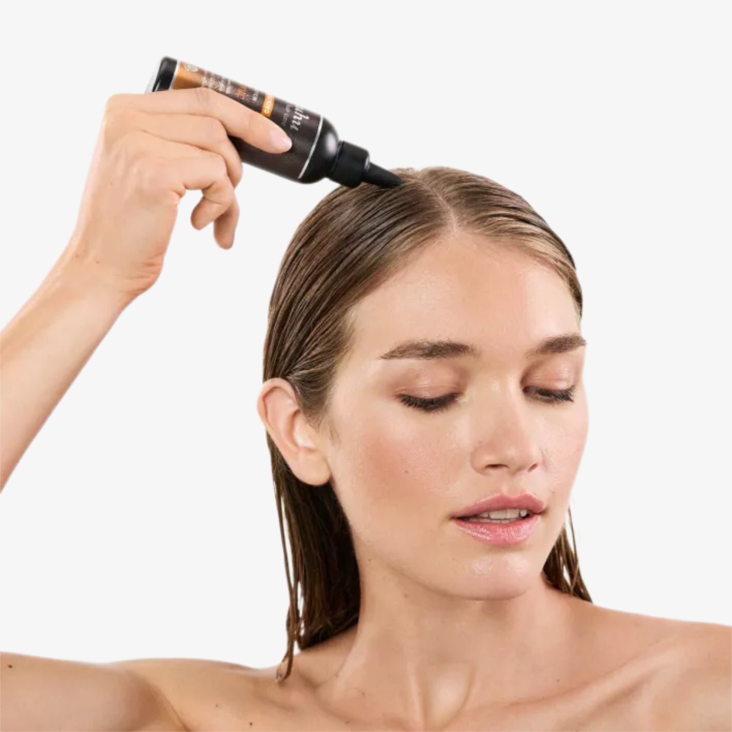 Eine Frau trägt Haarserum auf ihren Scheitel auf und hat die Augen geschlossen.