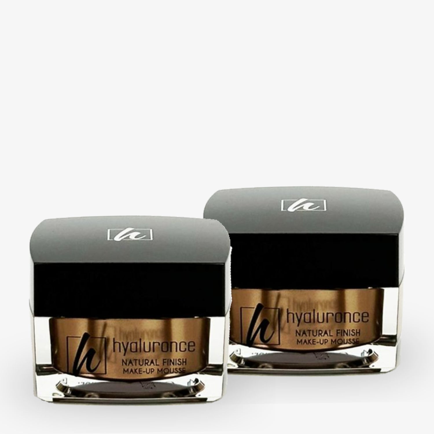 Zwei Gläser mit Hyaluronce Natural Finish Make-up Mousse mit schwarzen Deckeln auf weißem Hintergrund.