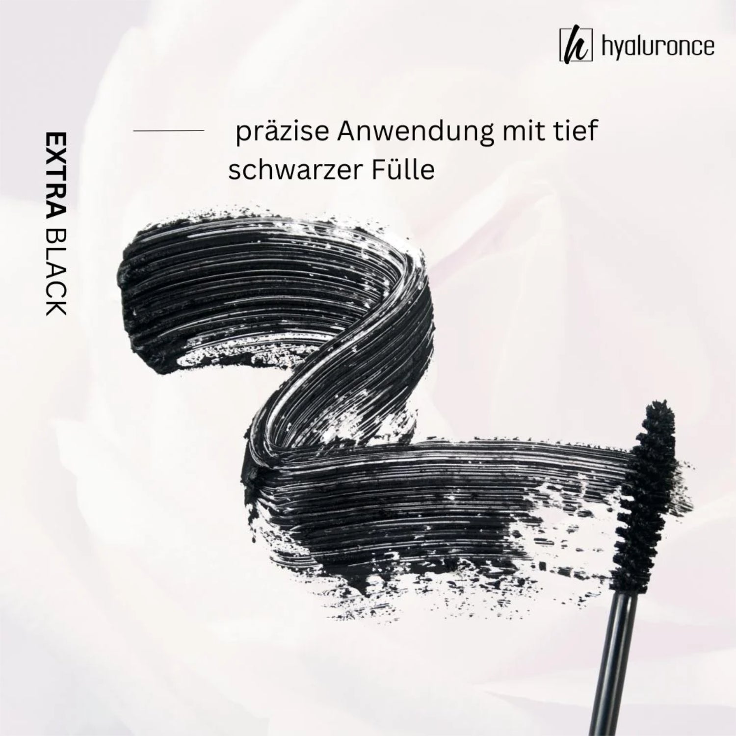 Ein schwarzer Mascara-Abstrich mit Bürste, beschriftet mit "präzise Anwendung mit tief schwarzer Fülle".