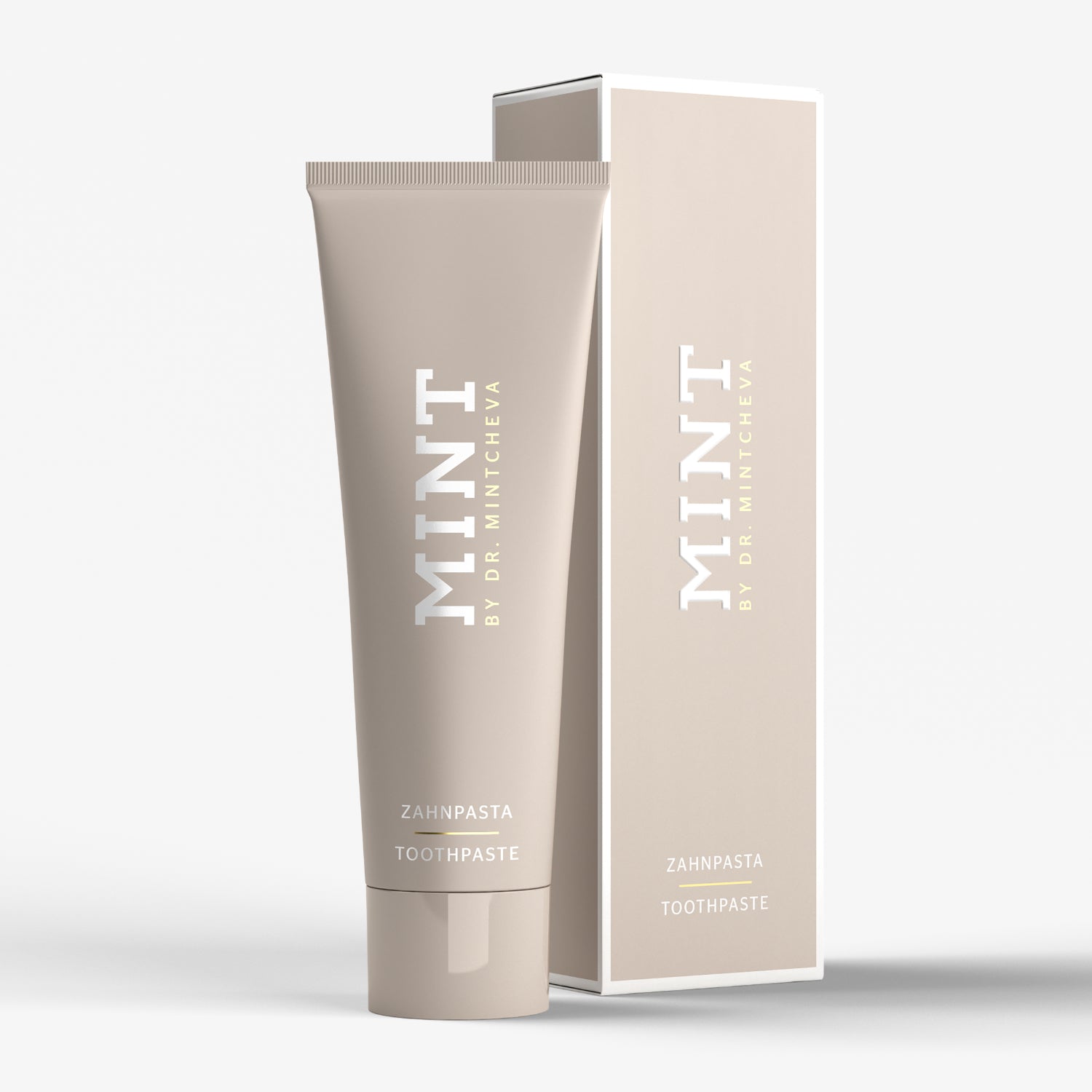 Beige Tube und Verpackung von Zahnpasta mit der Aufschrift "MINT BY DR. MINTCHEVA" auf weißem Hintergrund.