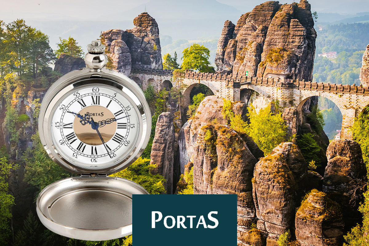 Taschenuhr vor der Bastei-Brücke in der Sächsischen Schweiz mit dem Wort "PORTAS" im Vordergrund.