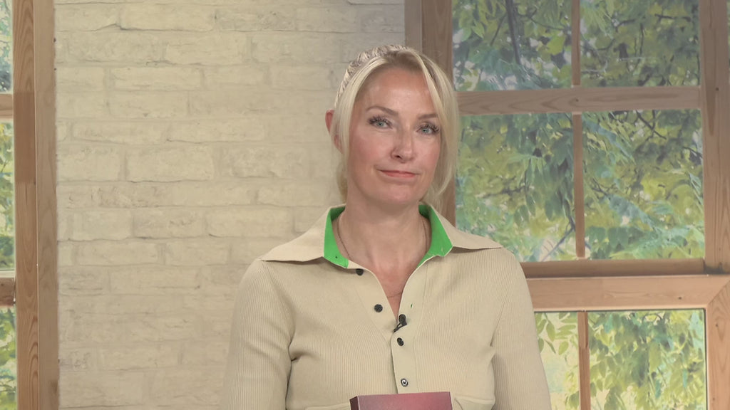 Video-Vorschaubild: Blonde Moderatorin hält eine dunkelrote Box oder ein Buch vor einer Backsteinwand und einem Fenster, unten rechts das premiumshopping.tv-Logo mit Telefonnummer.