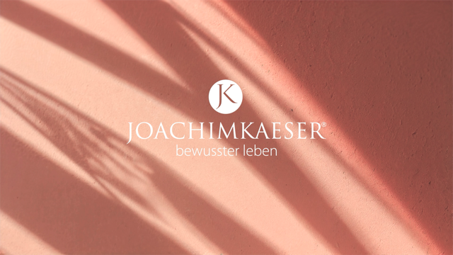 Zwei Personen in Tanzhaltung; Mann in weißem Hemd, Frau in schulterfreiem Campingkleid, vor einer grauen Wand.